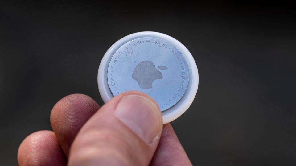 Un dispositivo Apple AirTag en los dedos de un hombre