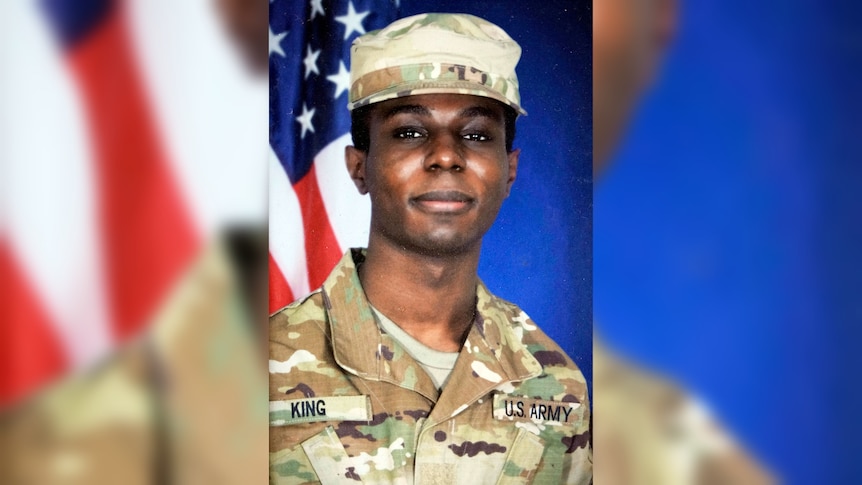 A photo of Travis King in army uniform, standing in front of an American flag. He is a black man in his 20s with dark eyes.