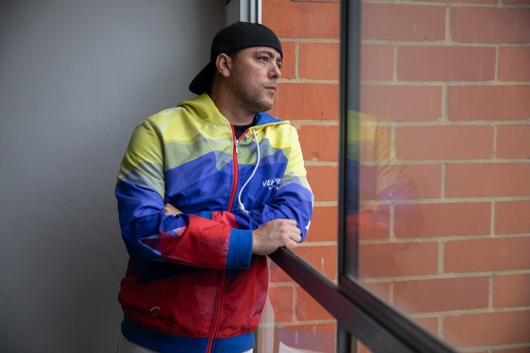 Jesús Medina mira por una ventana abierta cerca de una pared de ladrillos